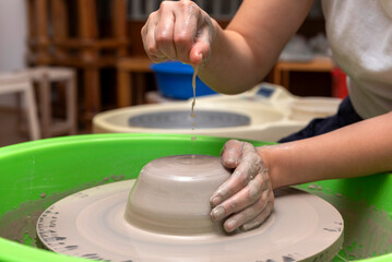 The process of kneading and manufacturing artisanal ceramics and clay by hand and with a wheel, showing the step-by-step process by the hands of a ceramics professional.
