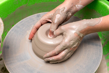 The process of kneading and manufacturing artisanal ceramics and clay by hand and with a wheel, showing the step-by-step process by the hands of a ceramics professional.

