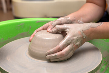 The process of kneading and manufacturing artisanal ceramics and clay by hand and with a wheel, showing the step-by-step process by the hands of a ceramics professional.
