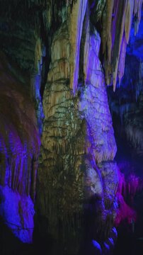 The bright and colorful Abrskil cave. A gallery-type cave in the mountains of Abkhazia with many stalactites and stalagmites, colorful lighting. Otapskaya (Otap cave). 4K