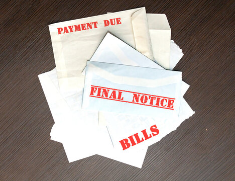 Large pile of envelopes with unpaid bills with warnings in red letters