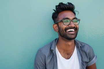Portrait of a cheerful indian man in his 20s laughing isolated in plain cyclorama studio wall