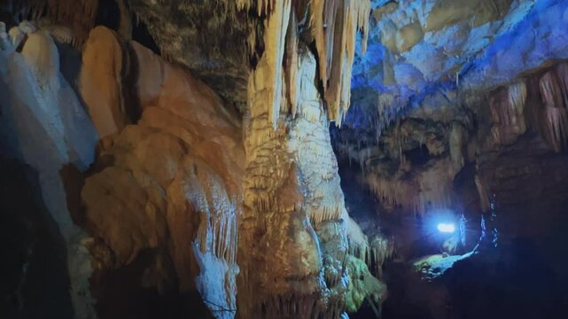 The bright and colorful Abrskil cave. A gallery-type cave in the mountains of Abkhazia with many stalactites and stalagmites, colorful lighting. Otapskaya (Otap cave). 4K
