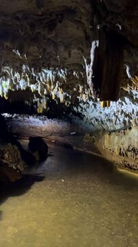 The bright and colorful Abrskil cave. A gallery-type cave in the mountains of Abkhazia with many stalactites and stalagmites, colorful lighting. Otapskaya (Otap cave). 4K