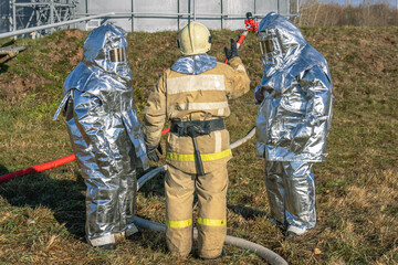 Firefighters in protective suits take up positions to extinguish the fire. Firefighters in...