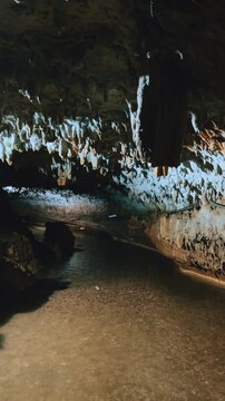 The bright and colorful Abrskil cave. A gallery-type cave in the mountains of Abkhazia with many stalactites and stalagmites, colorful lighting. Otapskaya (Otap cave). 4K