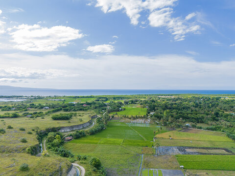 East Sumba, East Nusa Tenggara, Indonesia – 04. 03. 2025 – In the valley between rocky hills, there lies a green rice field in East Sumba  - Powered by Adobe