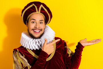 Smiling young man in royal medieval costume posing against a vibrant yellow background