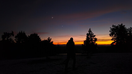 Silhouette of a man observing Milky Way stars from a dark countryside location..