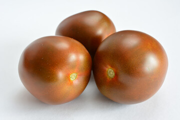 Obraz premium Three dark brown tomatoes isolated on white
