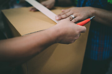 warehouse worker checking cardboard box quality. team worker using cutter to open inside crate...