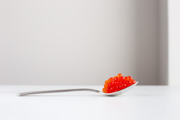 Vibrant red caviar on silver spoon against minimalist background in a modern kitchen setting