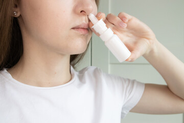 Close up of a woman applying a nasal spray to relieve congestion, seasonal allergies, runny nose,...