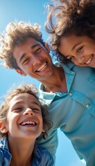 A cheerful young man is surrounded by two smiling children, all radiating happiness against a clear blue sky. This heartwarming scene captures the essence of family joy and carefree moments