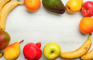 Frame of fresh fruit creating empty space on white wooden table