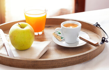 Delicious breakfast with coffee, juice and apple on wooden tray