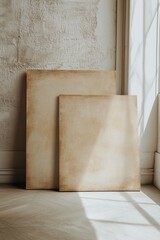 Blank canvases resting in a sunlit corner of a minimalistic room with textured walls