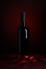 Bottle of red wine on dark red background. Front view