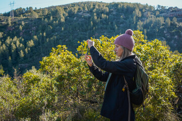 Hiker taking pictures of plants during a mountain trekking excursion on a sunny day