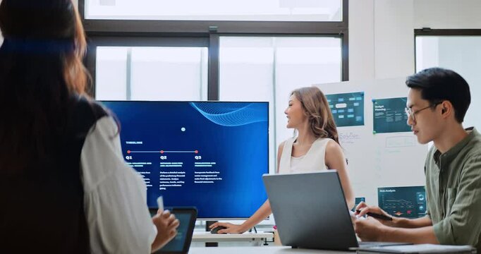 Group of Asian generation z business people work together in home office. Financial team businesspeople brainstorm meeting, use laptop computer and presentation screen. Corporate teamwork concept