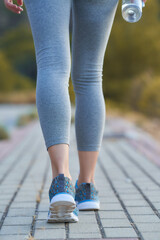 Walking along a pathway with fitness attire, hydration, and determination in a natural setting during a sunny day