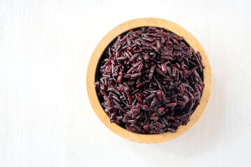 Steamed black sticky rice in wooden bowlon white background