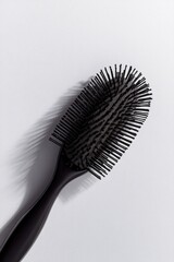 sleek black hairbrush with natural bristles placed diagonally on white background emphasizing elegance and quality