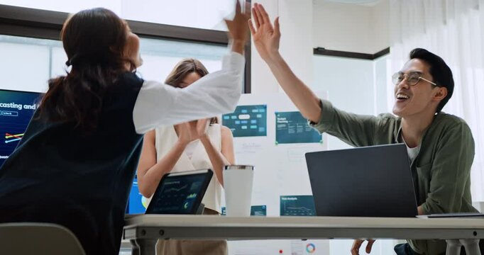 Group of Asian generation z business people work together in home office. Financial team businesspeople brainstorm meeting, team high-five clap hands celebrate success. Corporate teamwork concept