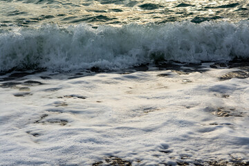 Splash of sea waves crashing on a pebble beach. Warm summer evening on the Black Sea coast