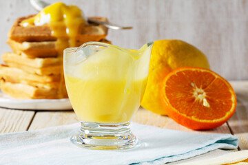 Lemon-tangerine curd in a glass gravy boat, tangerine and lemon and Belgian waffles.