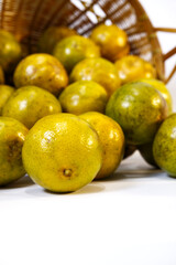 Orange or Bang Mot tangerine orange with blur basket on white background. Close-up Bang Mot tangerine texture in vertical. Freshness, healthy fruit, citrus, plant, tropic and rustic kitchen concepts.