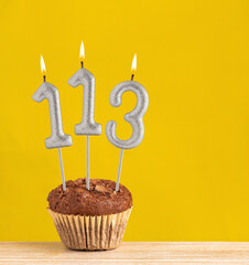 Chocolate cupcake with number 113 candle - Birthday on a yellow background.