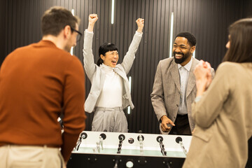 Joyful celebration among friends during a foosball game in a stylish indoor setting