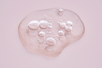 Textured drop of serum with bubbles on pink background.