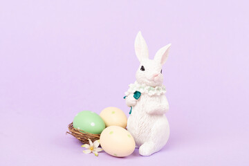 Easter bunny with painted eggs on color background