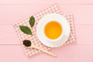 Cup of tea with dry and fresh leaves on wooden background, top view