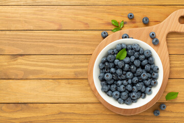 Bowl with fresh bright blueberries on wooden background,top view