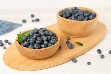 Bowl with fresh bright blueberries on wooden table