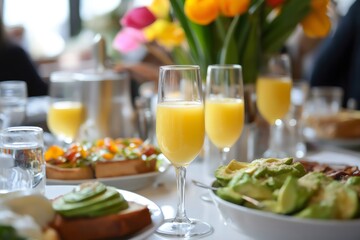 Glasses of mimosas cocktails are served with avocado toast and other dishes during a celebratory brunch
