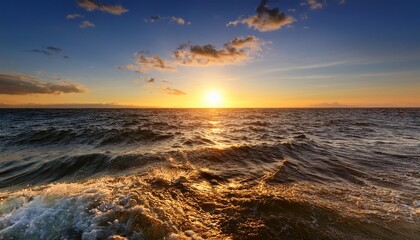 Obraz premium the sun descends towards the horizon casting a warm glow on the ocean surface as gentle waves create a sparkling effect in the evening light