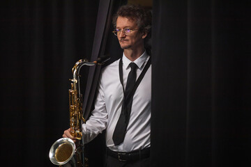 Medium full shot of contemporary jazz male musician of middle age dressed in elegant concert attire...