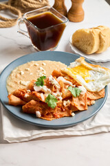 Delicious chilaquiles with fried egg and refried beans for authentic mexican breakfast