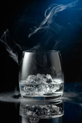 Vodka with ice on a black reflective background.