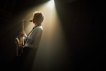 Side view of professional male jazz musician in white shirt playing saxophone creating enchanting...