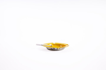 A cigarette burning in a vintage ashtray on a white background