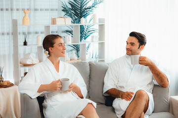 Fototapeta premium Beauty or body treatment spa salon vacation lifestyle concept with couple wearing bathrobe relaxing with drinks in luxurious hotel spa or resort room. Vacation and leisure relaxation. Quiescent