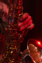 Vertical close up shot of male saxophonist playing enchanting jazz music pushing keys of shiny...