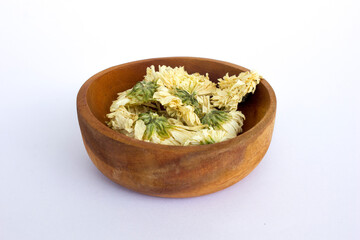 Dried Chrysanthemum flowers tea in wooden bowl, isolated on white background.