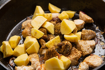 Cholent with potatoes, onions, meat and spices is stewed in a frying pan