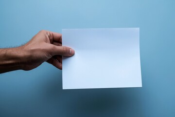 Fototapeta premium Hand Holding Blank White Paper Against Blue Background